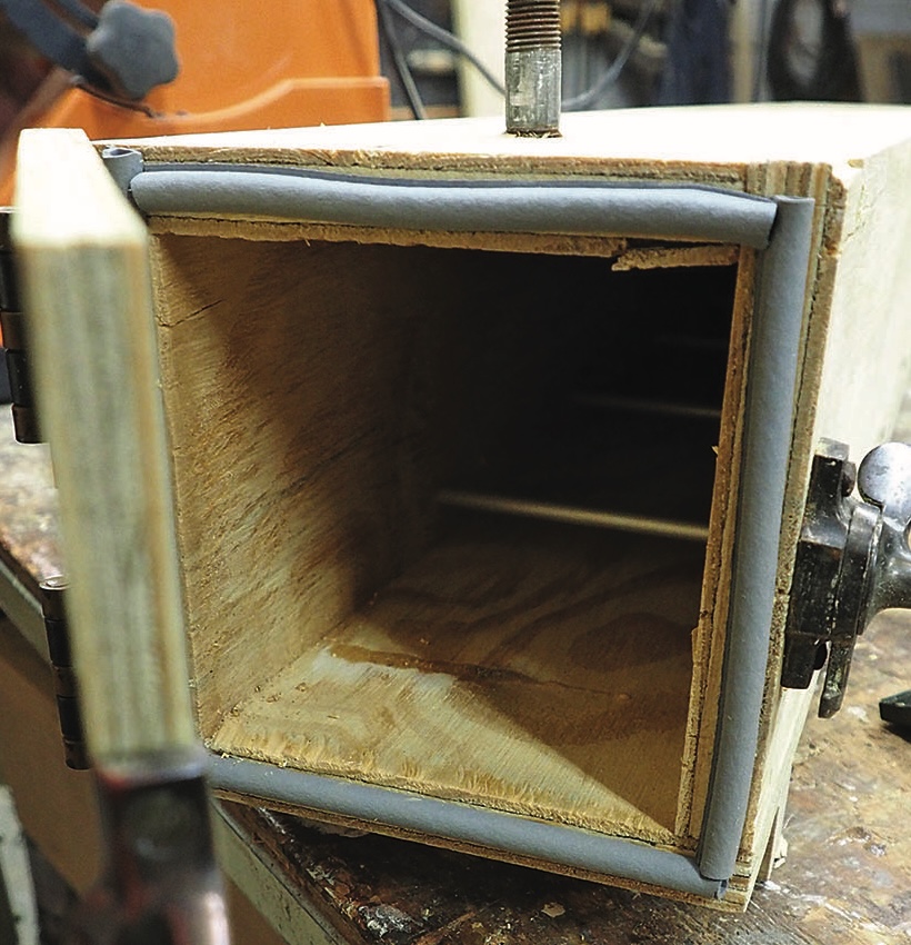 Open wooden box with clamps and sealant.