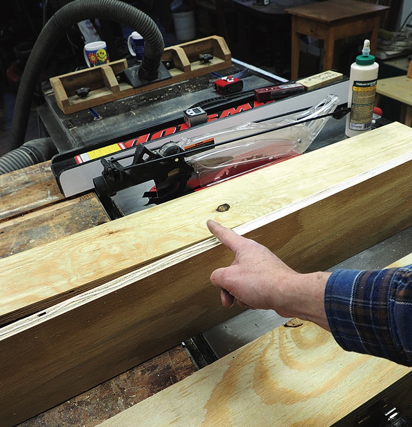 Person pointing at wooden board on table saw.