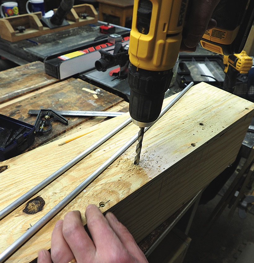 Person using drill on wooden plank in workshop.