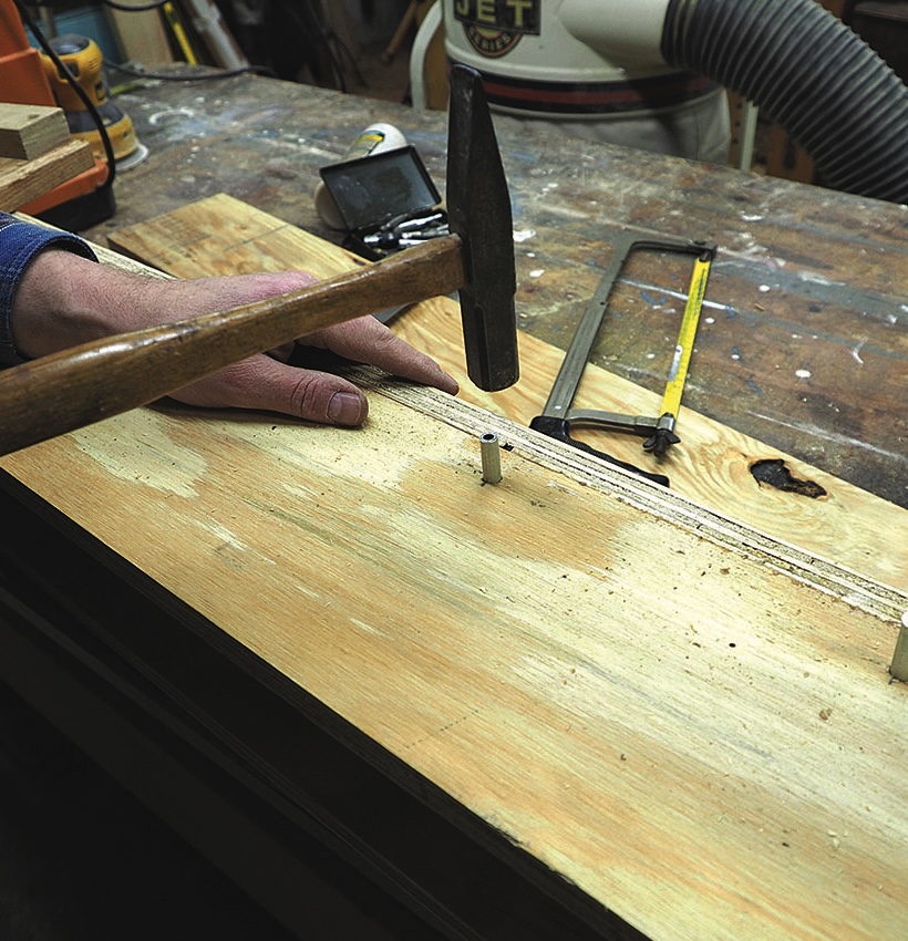 Hammering metal dowel into wooden board.