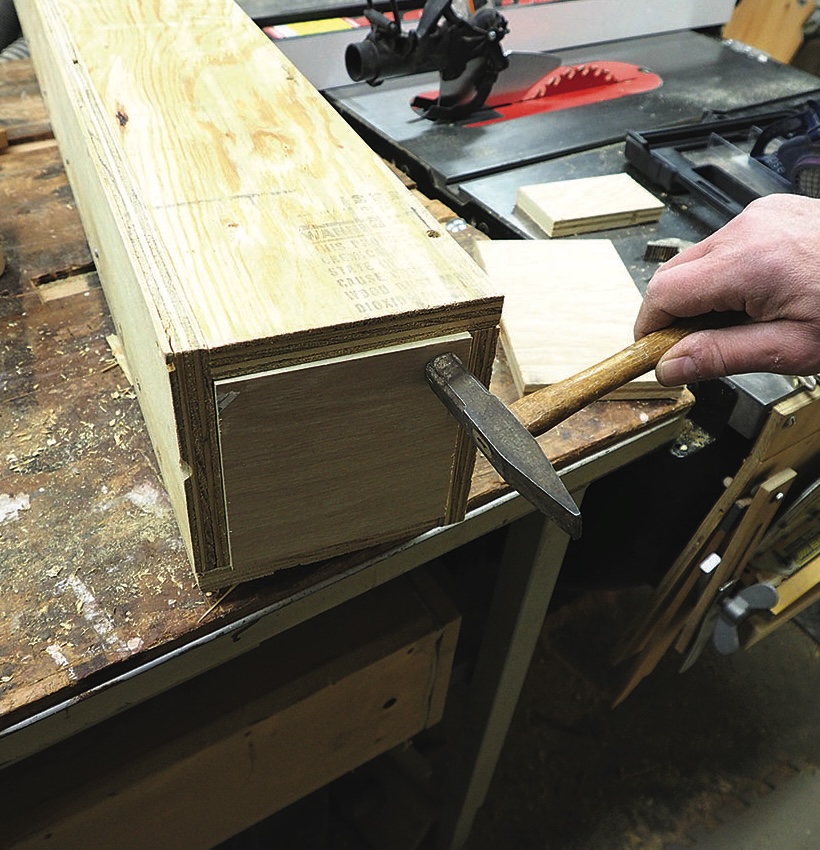 Person assembling wooden box with hammer.