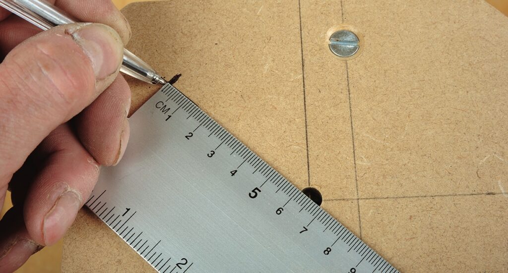 Person marking wood with metal ruler and pen.