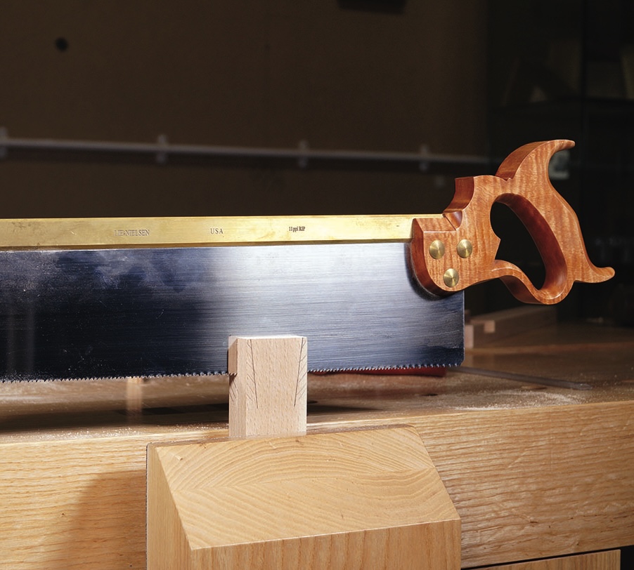 Close-up of a hand saw on a wooden surface.