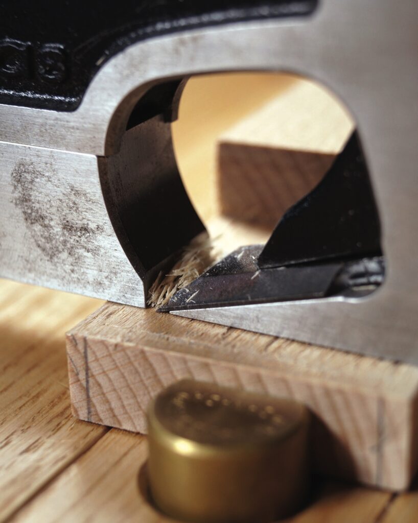 Close-up of precision woodworking hand tool in use.