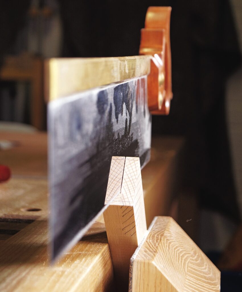 Close-up of saw cutting dovetail joint in wood.