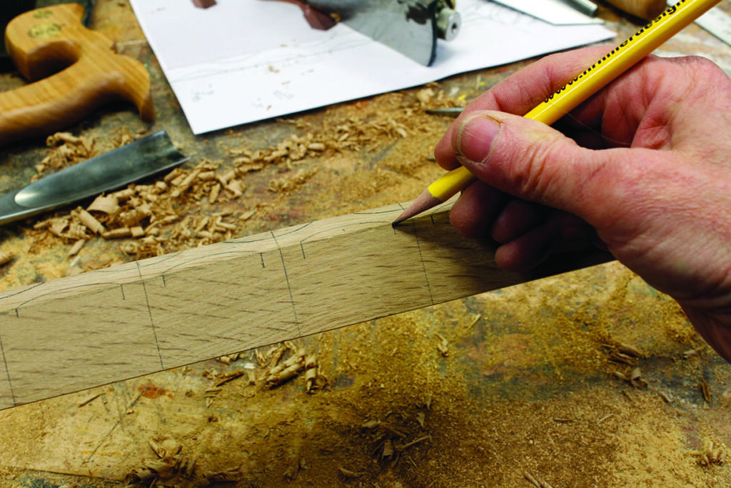 Person drawing lines on wood plank with pencil.