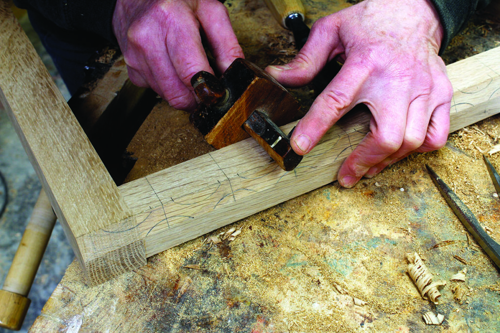 Carpenter planing wood with hand tool, workshop scene.