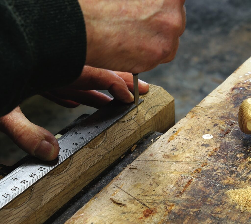 Person marking wood with ruler in workshop.