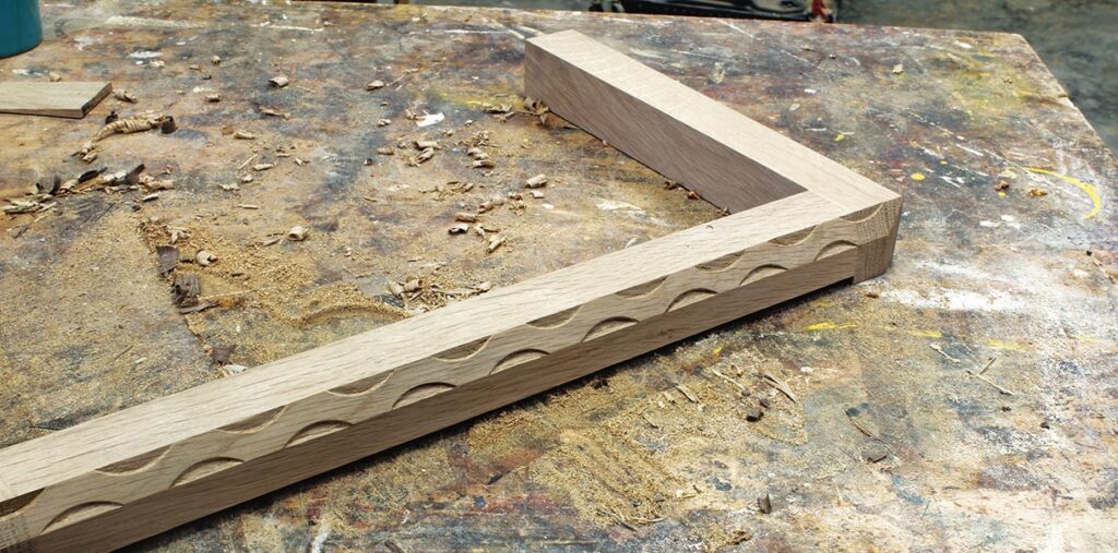 Woodwork frame with carved pattern on workbench.