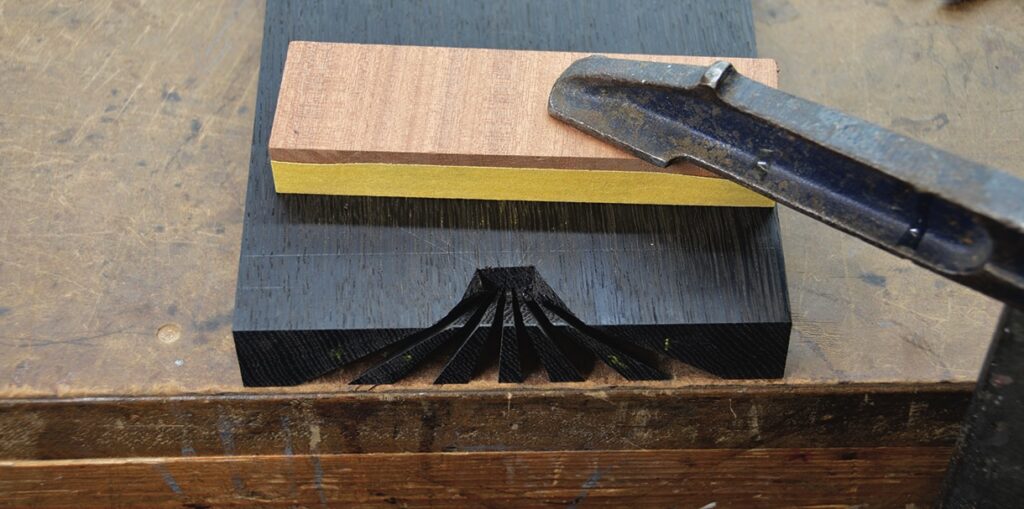 Carving dovetail joint in wood with chisel.