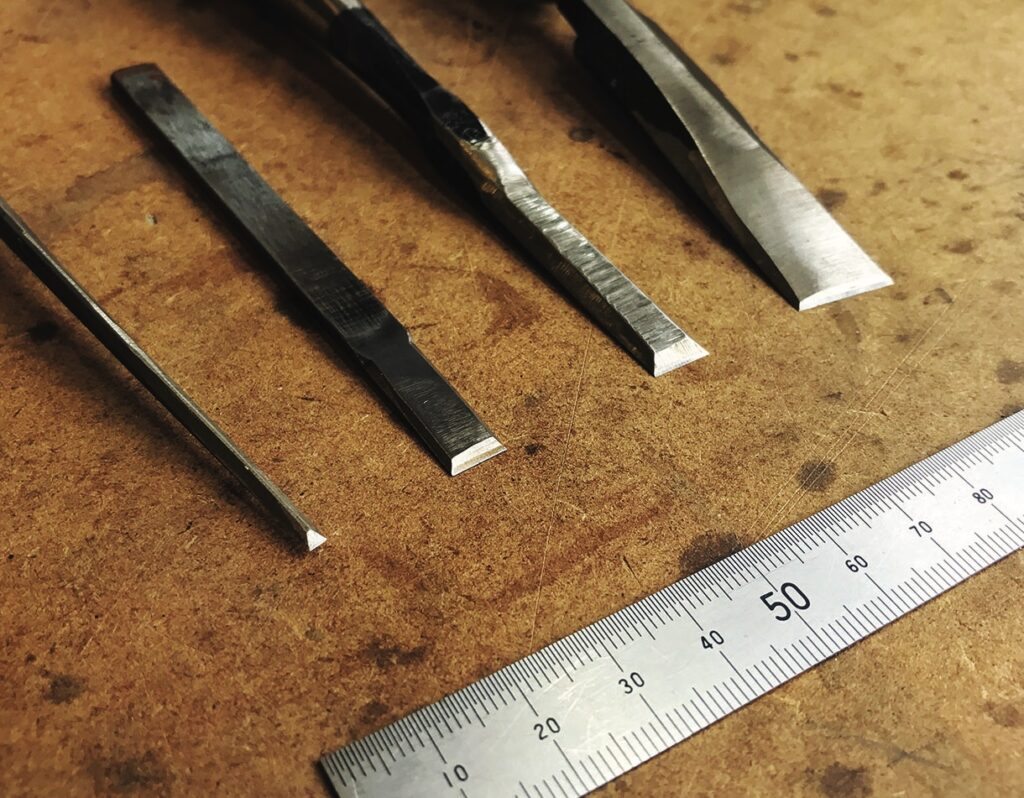 Woodworking chisels and ruler on wooden surface.