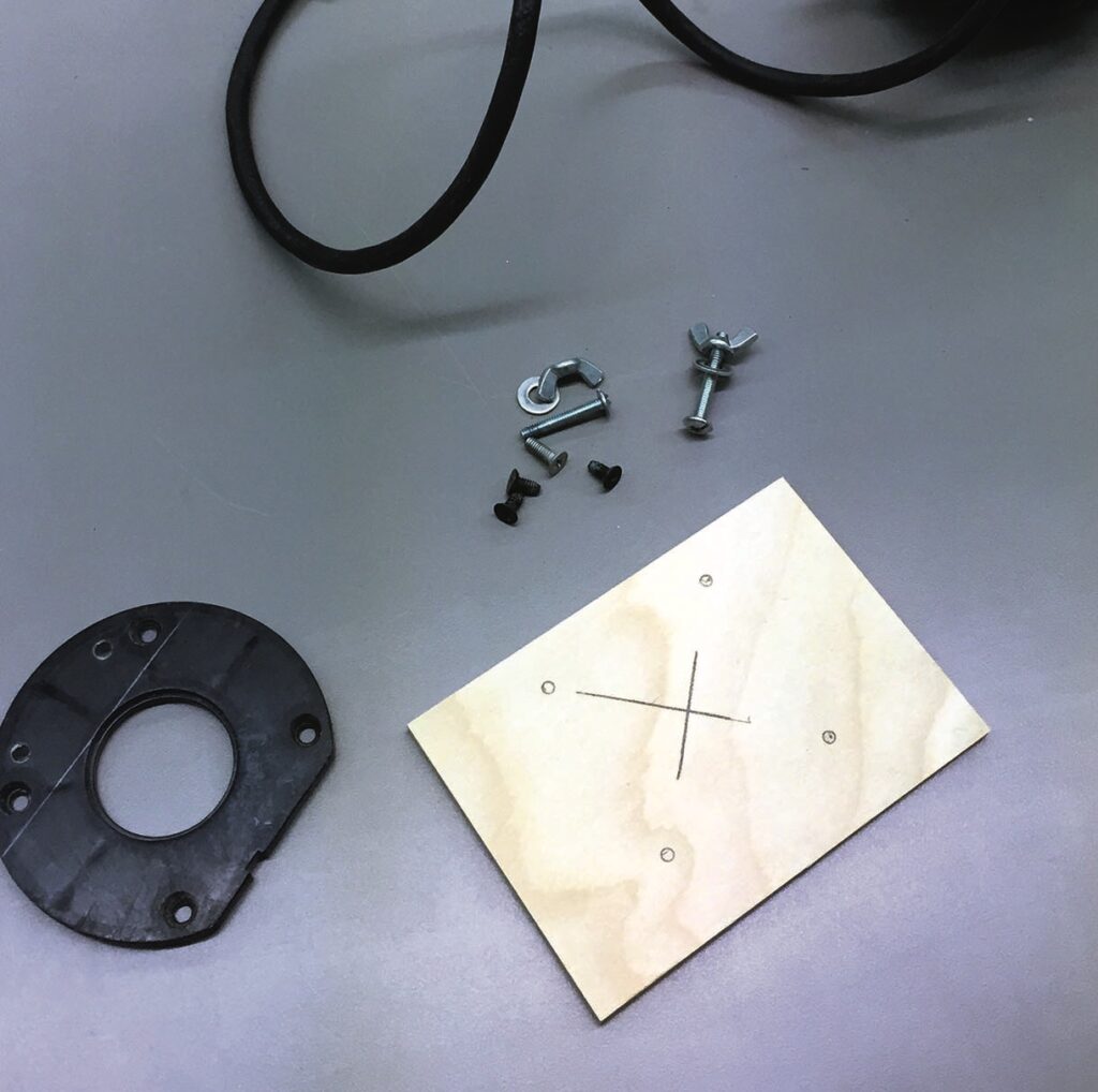 Assorted screws and wooden template on grey surface.