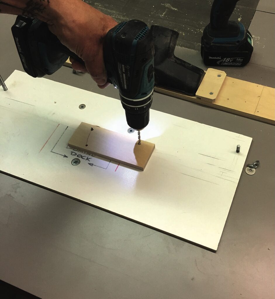 Person drilling a hole in wooden board.