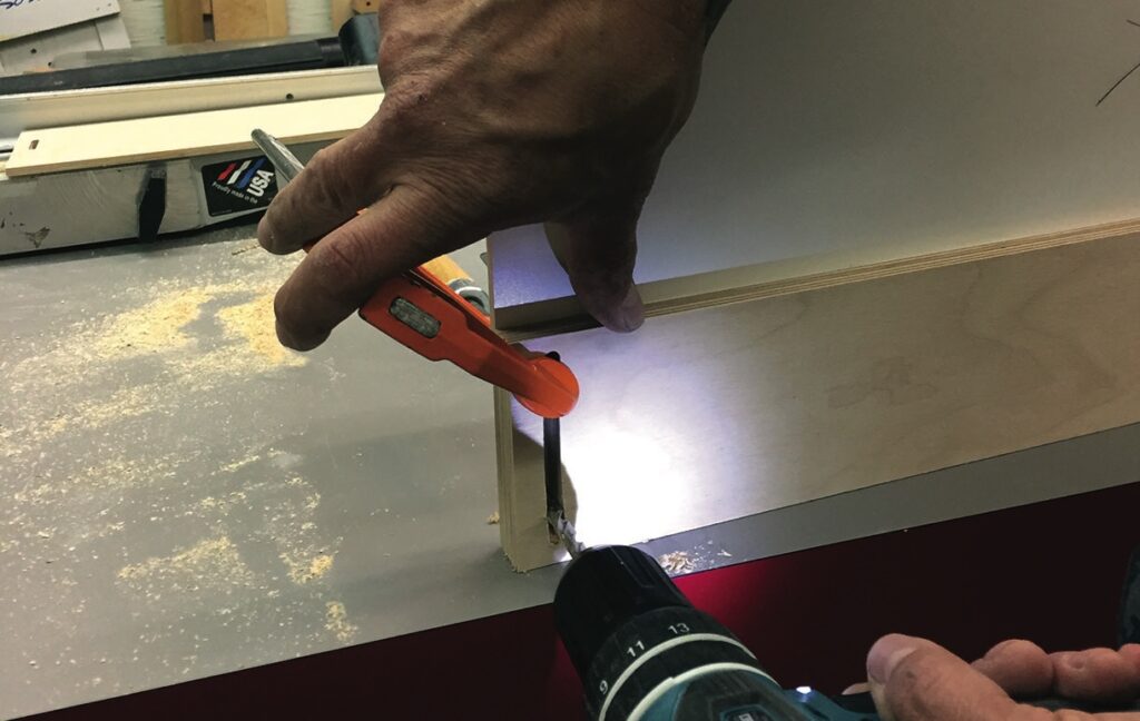 Person using drill and knife on wood board.