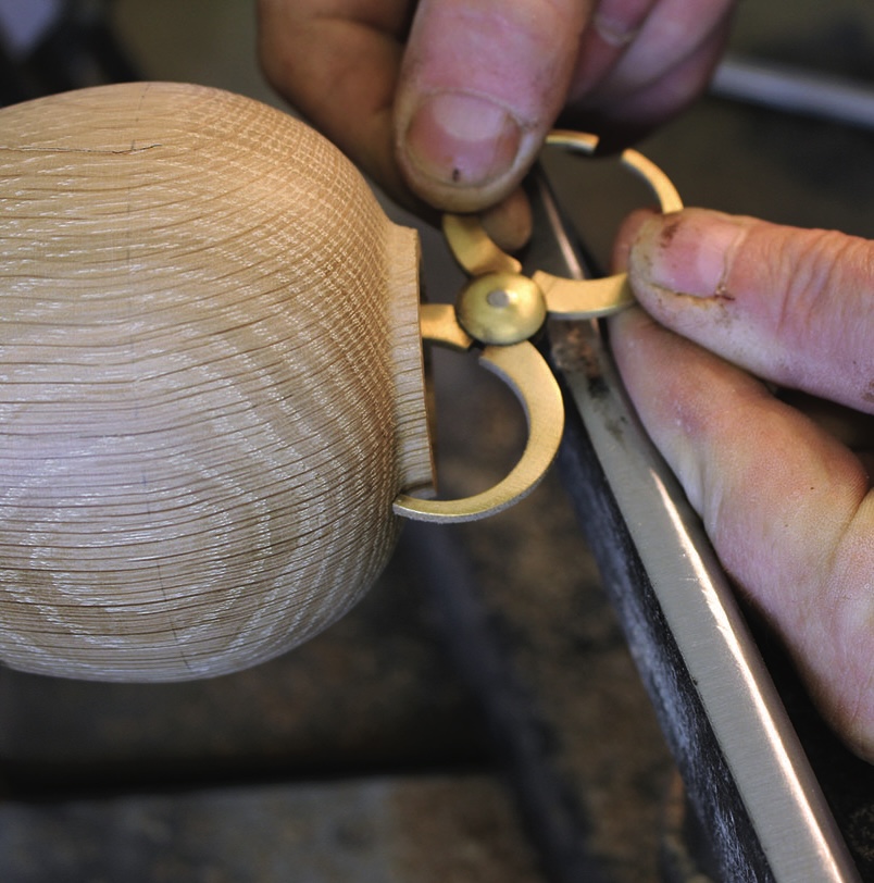 Craftsman measuring wooden object with callipers.