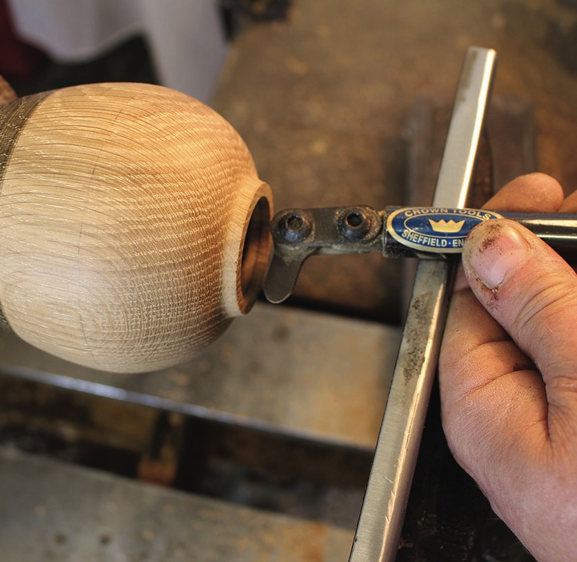 Woodturning with chisel on spinning wooden bowl.