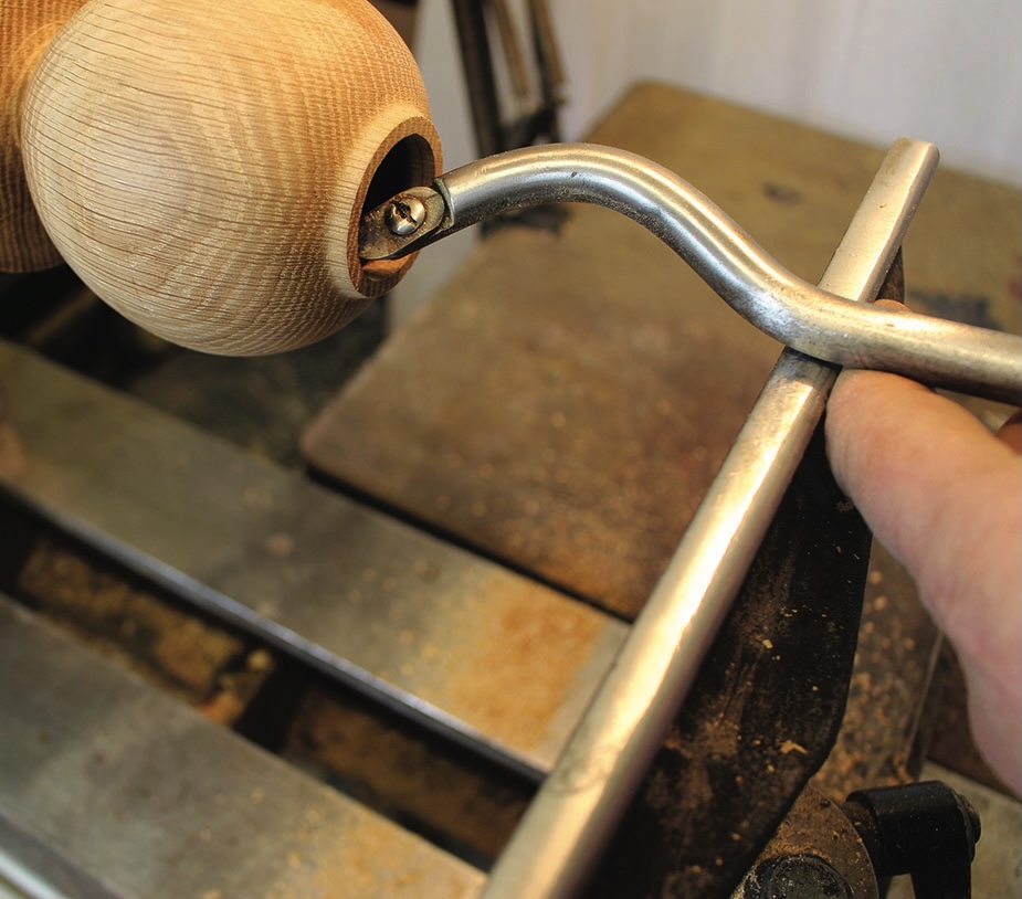 Woodturning tool shaping wooden piece on a lathe.