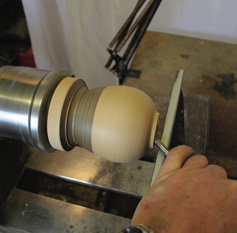 Woodturning process shaping a wooden sphere.