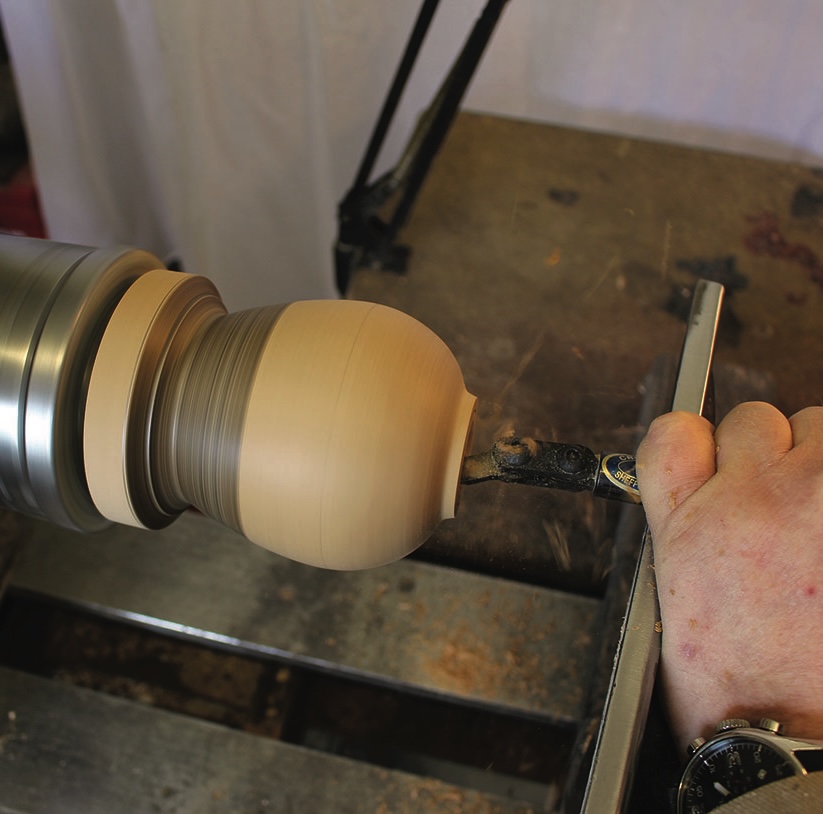 Woodturning a wooden sphere on a lathe.