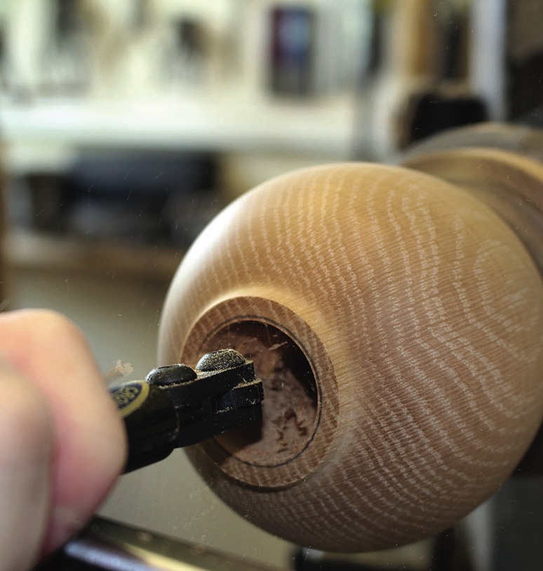 Person carving wooden object on a lathe.