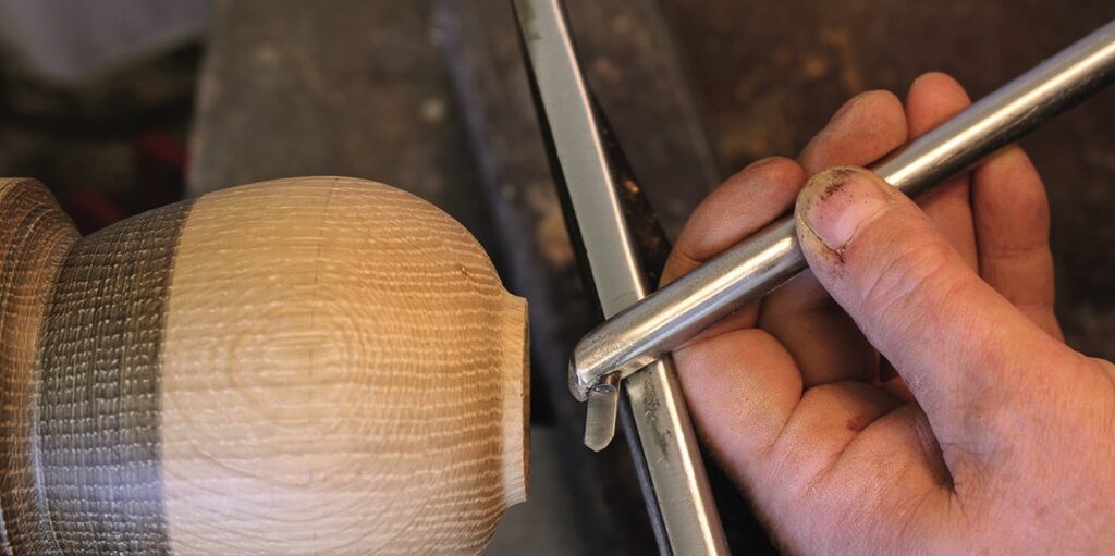 Person using chisel on wooden lathe project.