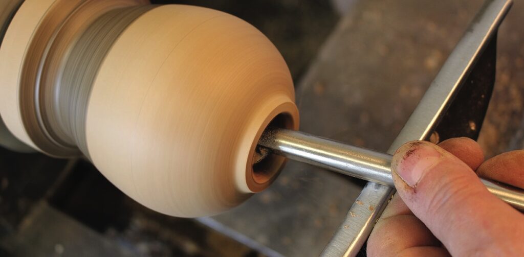Woodturning on a lathe with carving tool.