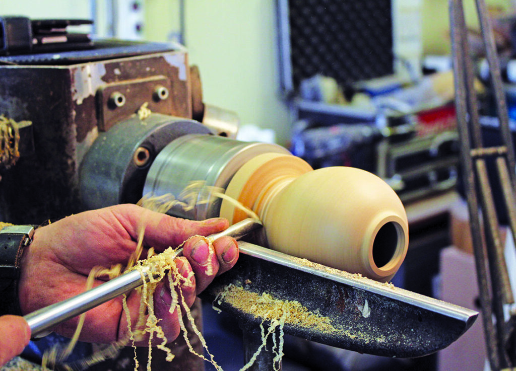 Woodturning wooden vase on a lathe machine.