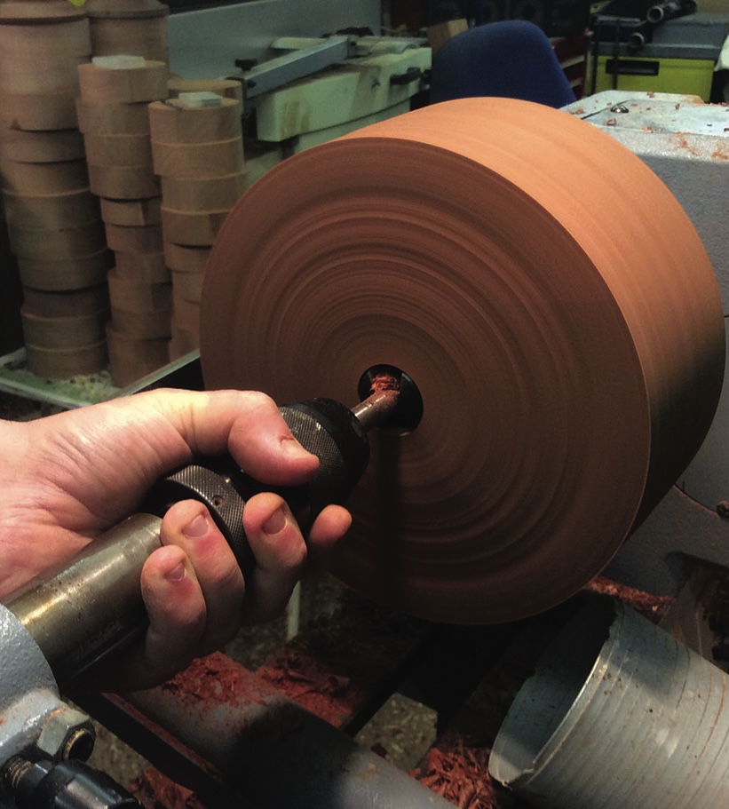 Person using a lathe to shape wooden disk.