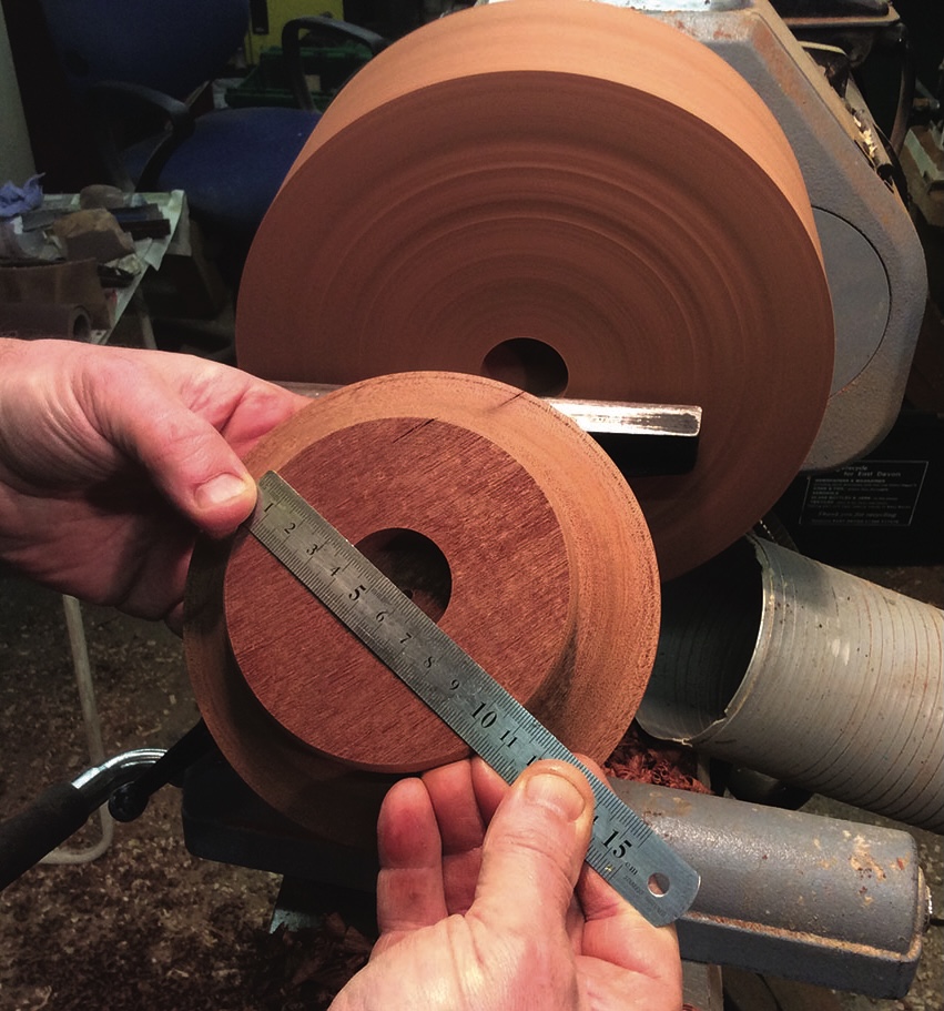 Measuring wooden disc on a lathe with ruler
