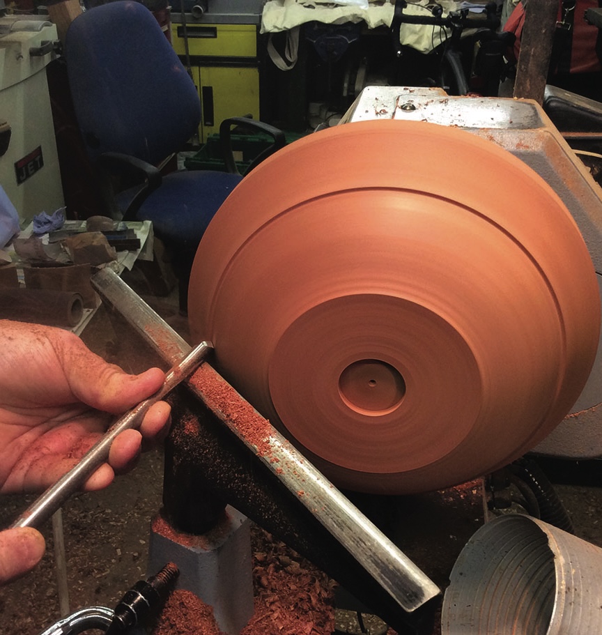 Woodturning on a lathe with handheld tool.