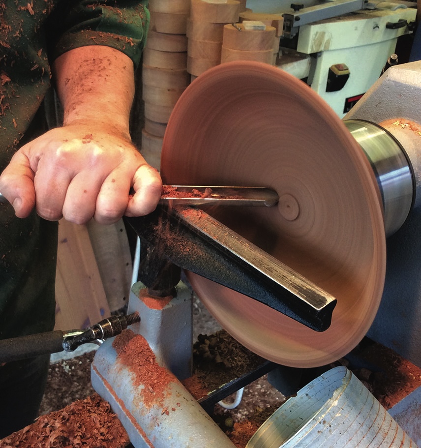 Woodturning on a lathe with chisel tool.