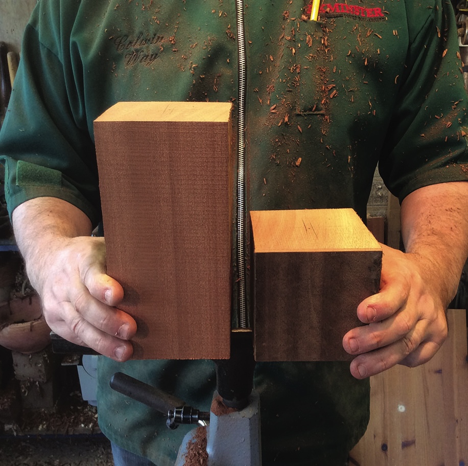 Person holding two large wooden blocks in workshop.