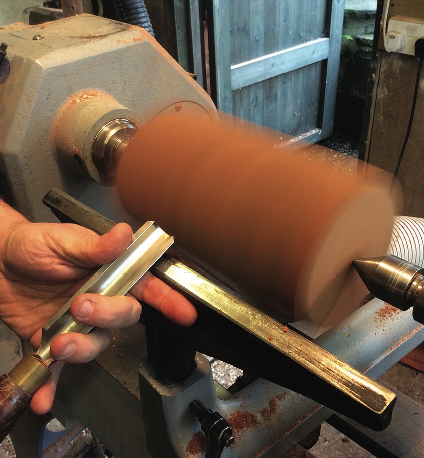 Lathe turning wood with metal chisel tool.
