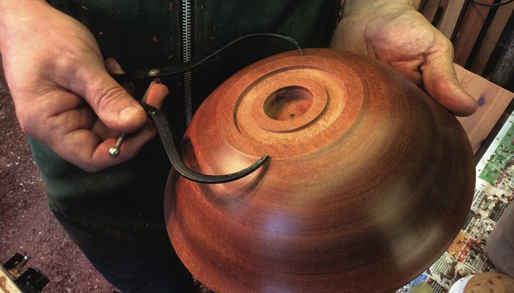 Person turning a wooden bowl with calipers