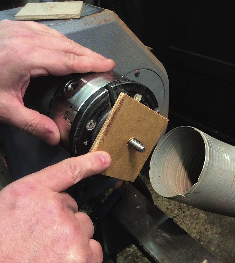 Wood lathe setup with hands and wooden attachment.