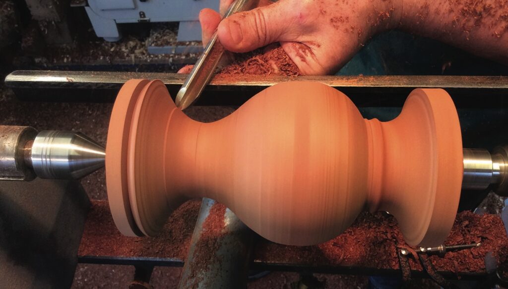 Woodturning vase on lathe with tool in use.