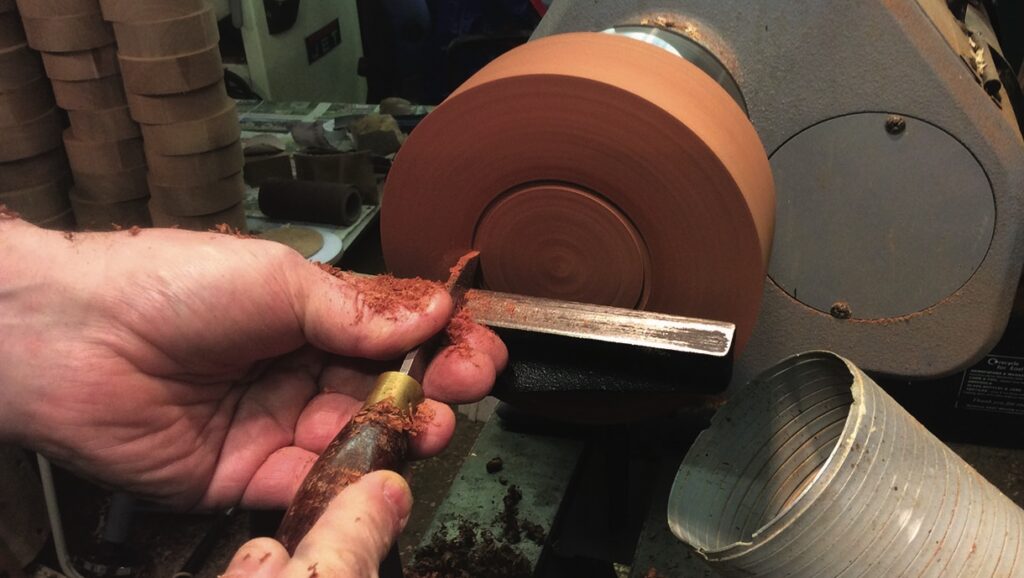 Woodturning with lathe and chisel in workshop.