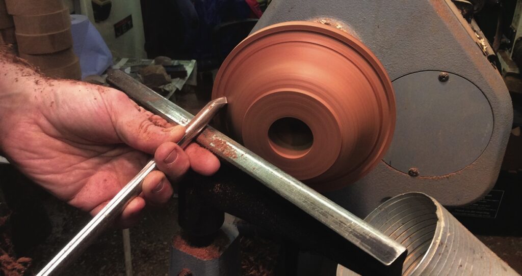 Woodturning on a lathe with hand chisel.