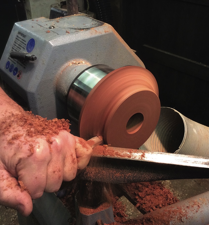 Woodturning on lathe with chisel and wood shavings.