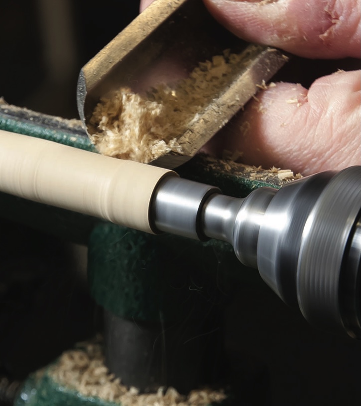 Woodturning with lathe and chisel, creating shavings.