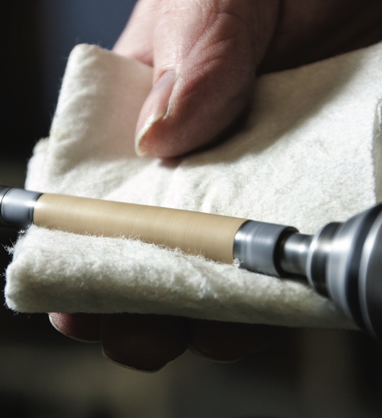 Hand polishing a wooden pen barrel.