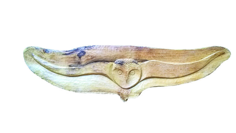 Wooden owl carving with wings spread wide.