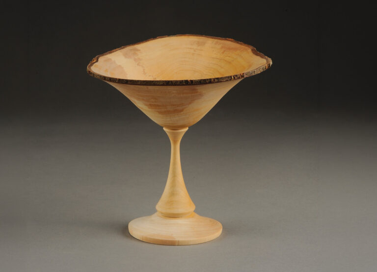Handcrafted wooden goblet on grey background.
