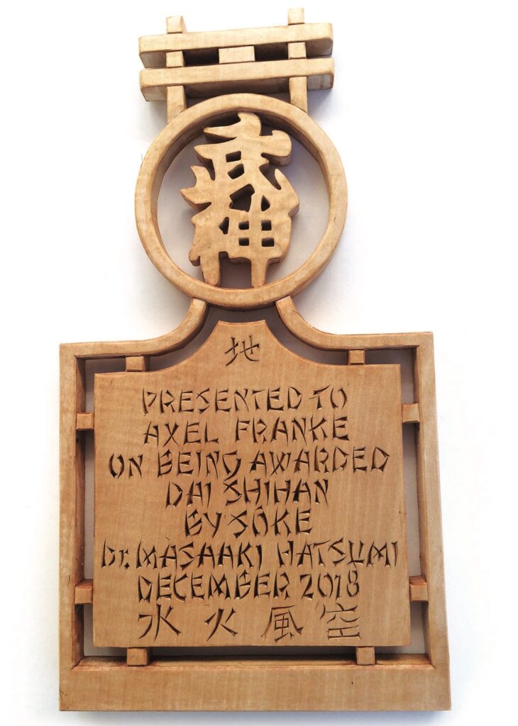Wooden award plaque with inscriptions and Japanese symbols.