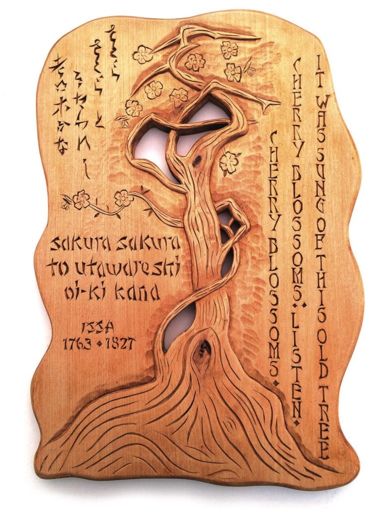 Wood carving with cherry blossom tree and inscriptions.