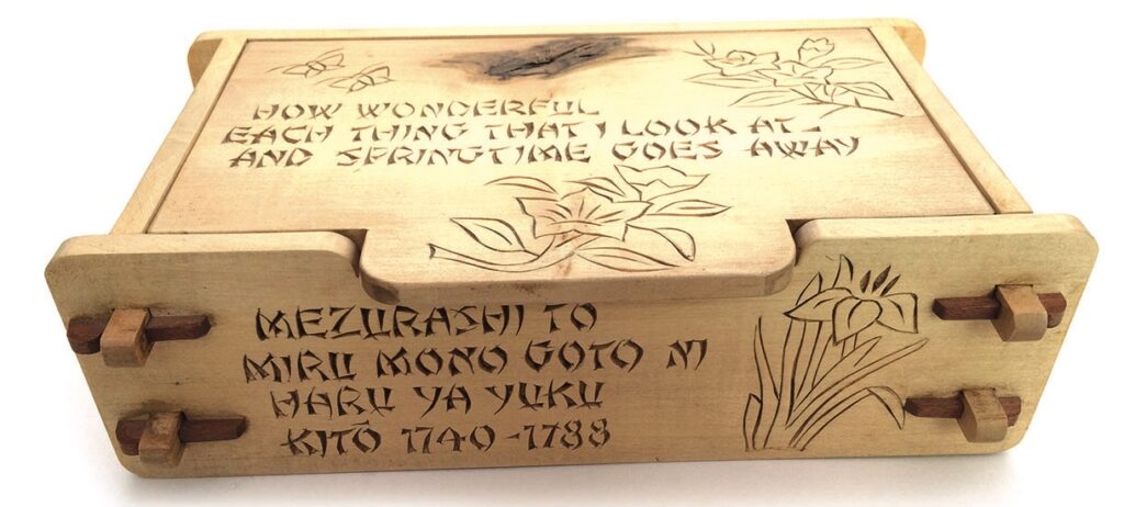 Wooden box with engraved floral design and text.