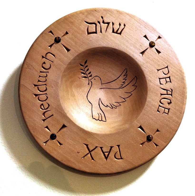 Wooden plate with dove and 'peace' in four languages.