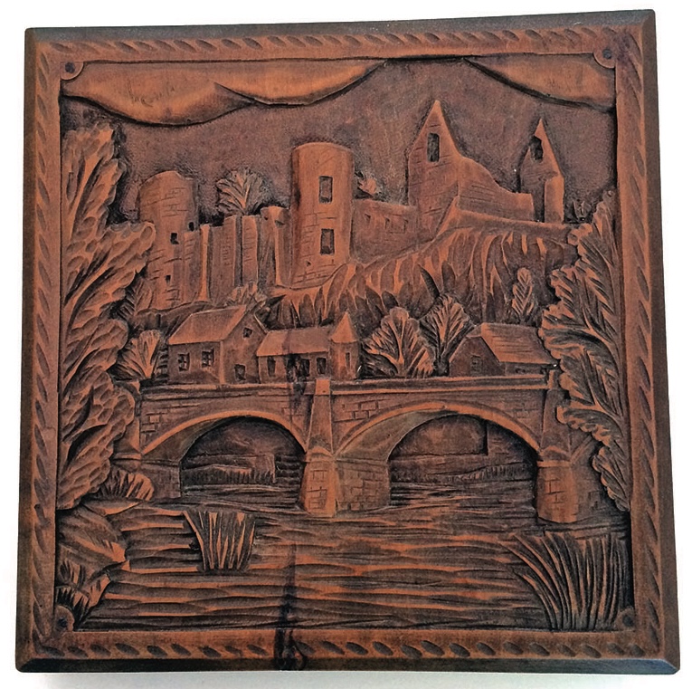 Wood carving of castle, bridge, and houses.