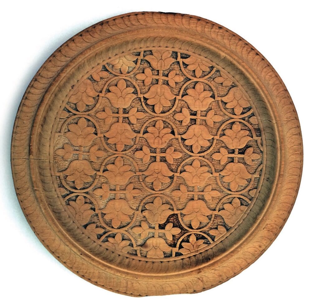 Hand-carved wooden plate with intricate floral design.