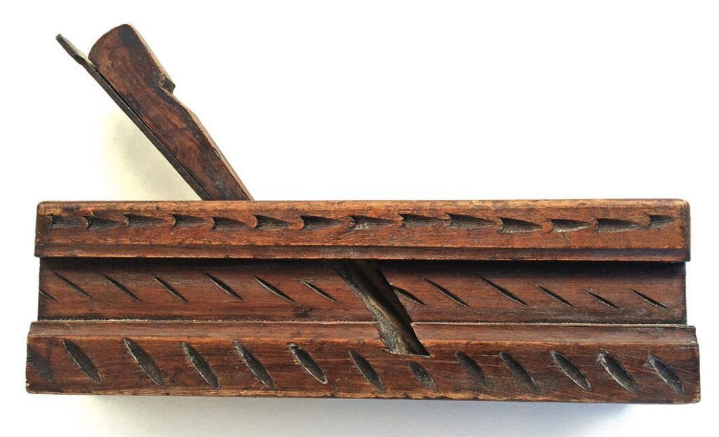 Antique wooden moulding plane with intricate carvings.